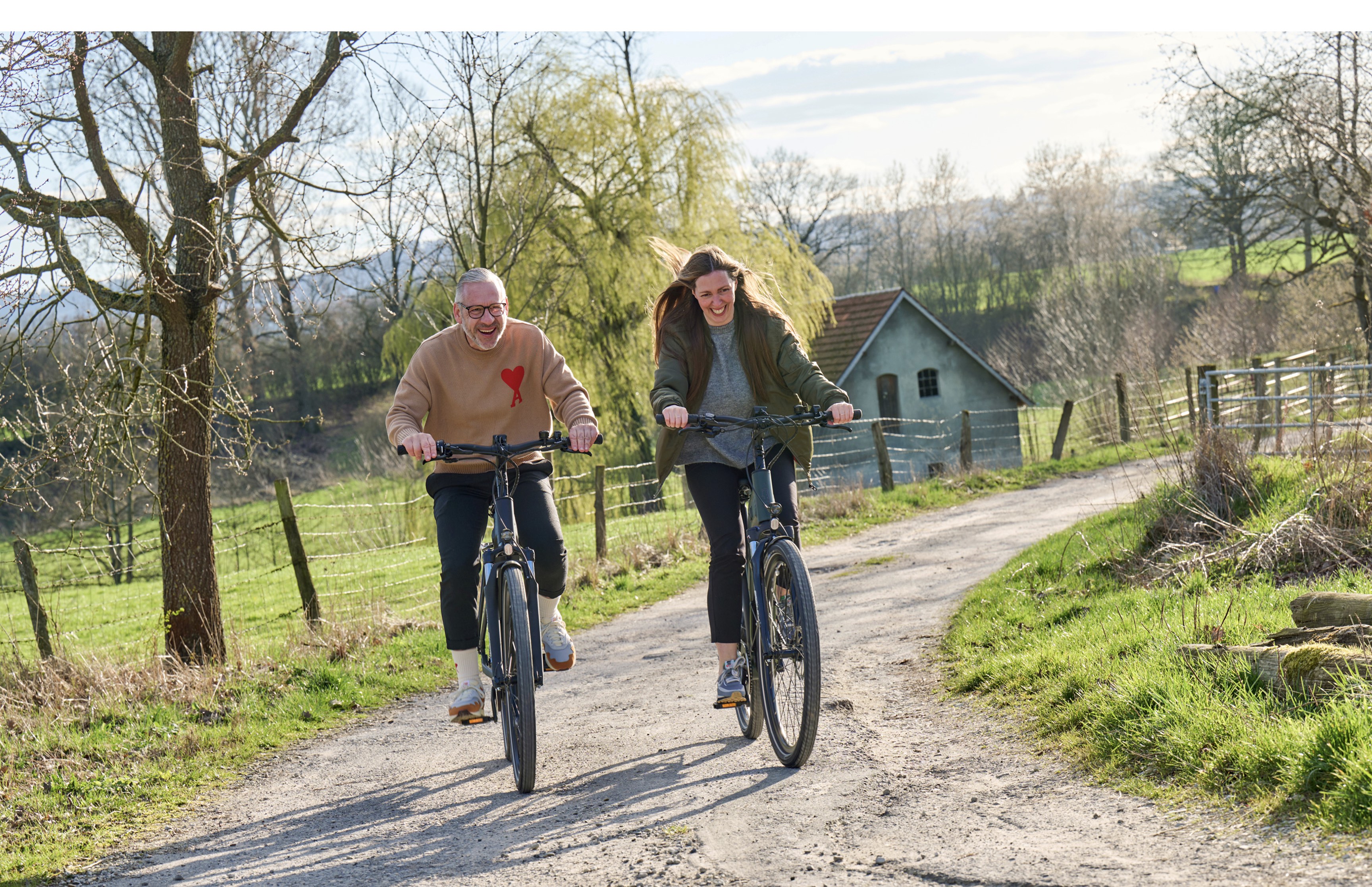 Zwei Personen fahren fröhlich E-Bike auf einem Feldweg – Lifestyle-Visual für Wittich Bikes, entwickelt von Neue Identität. Fotografie Sebi Ruthe.