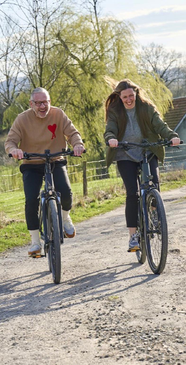 Zwei Personen fahren fröhlich E-Bike auf einem Feldweg – Lifestyle-Visual für Wittich Bikes, entwickelt von Neue Identität. Fotografie Sebi Ruthe.